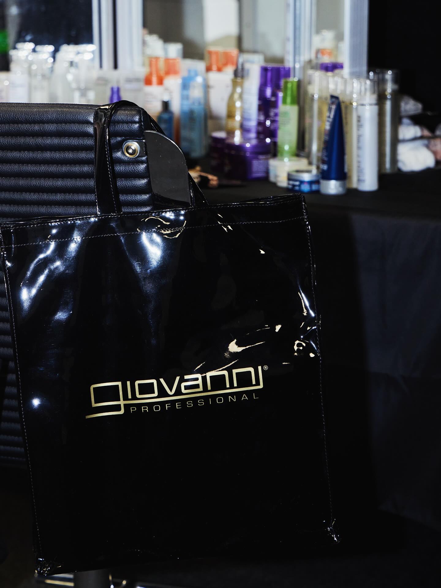 Black bag with 'Giovanni Professional' logo on a blurred background of Giovanni hair products.
