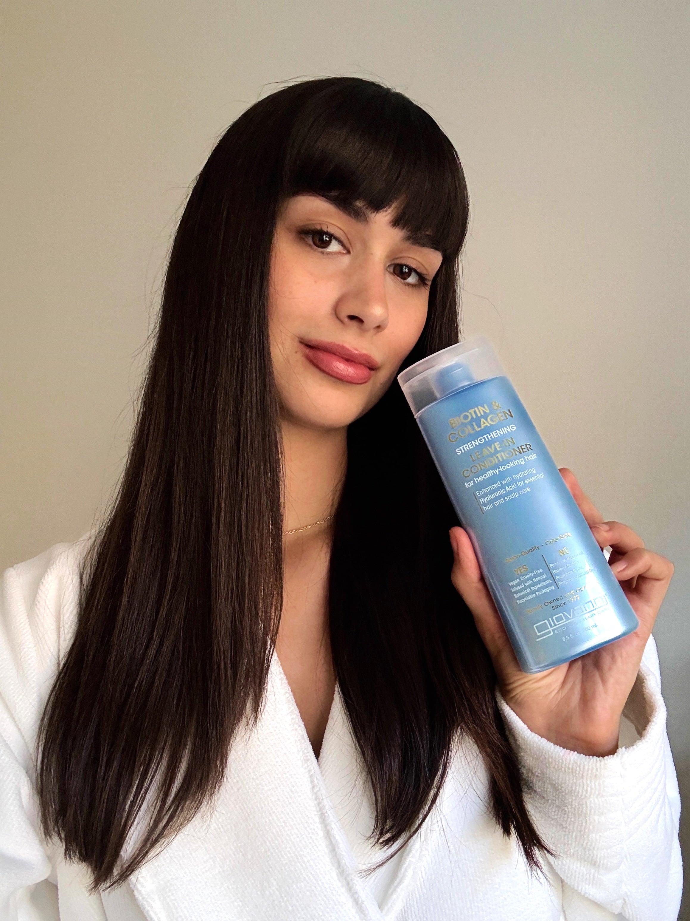 Woman holding a bottle of Giovanni Biotin & Collagen conditioner