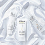 Three tubes and a spray bottle of Giovanni Cosmetics hair care, including NUTRAFIX™ HAIR RECONSTRUCTOR, are displayed on glossy white satin—ideal for color-safe, deep hair repair and nourishing treatments.